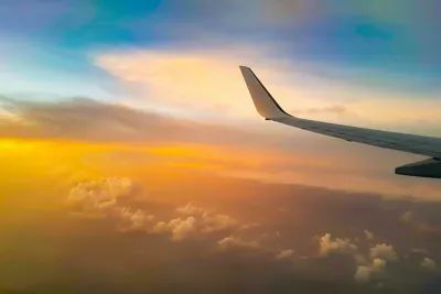 A plane wing with the sun setting in the background.